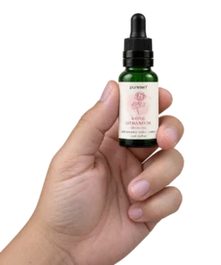 Puresen Rose Geranium 15 ml Aroma Oil held naturally between the fingers of an adult hand